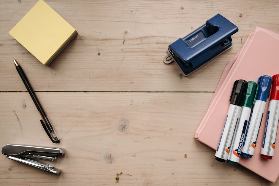Flat lay of office supplies on a wooden desk for a neat workspace setup.