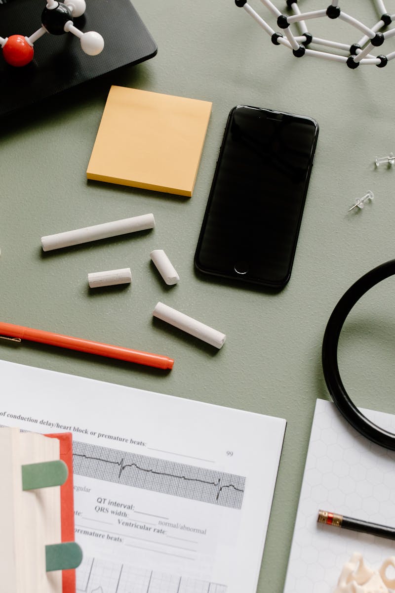 Flat lay of medical study desk with a stethoscope, books, and molecular models.